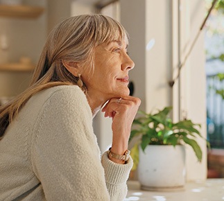 Senior woman smiling while looking out the window at home