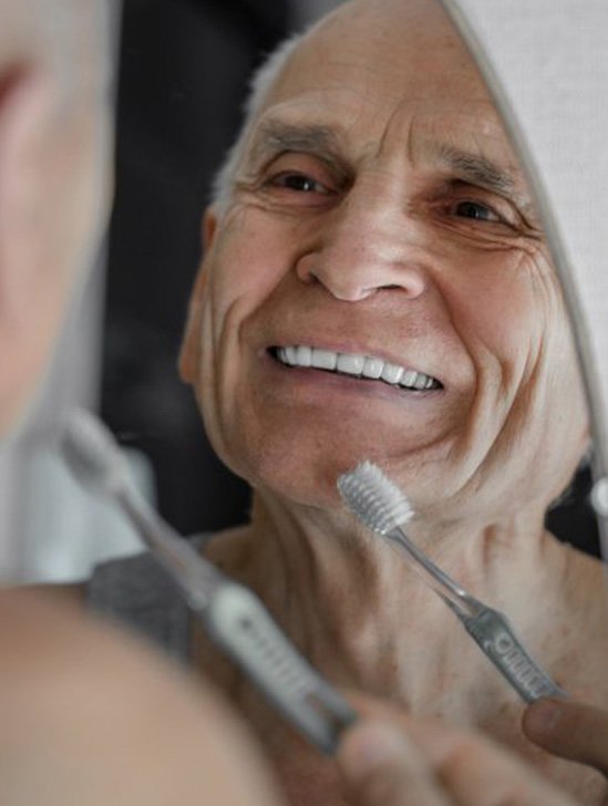 Man brushing his teeth in mirror