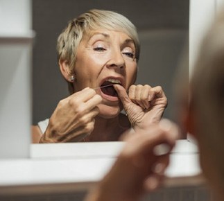 Woman flossing her teeth in mirror