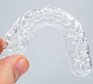 Fingers holding a mouthguard