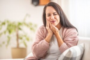 Woman holding side of face in pain from toothache.